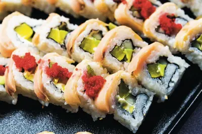 a pile of sushi sitting on top of a black plate at Riu Republica - Adults Only - All Inclusive in Punta Cana