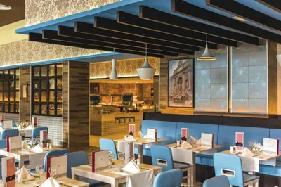 a restaurant with white tables and blue chairs at Riu Republica - Adults Only - All Inclusive in Punta Cana