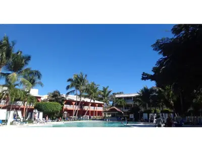 a large swimming pool with palm trees and buildings at Private room in the Boca Chica Resort condominium in Boca Chica
