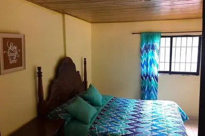a bedroom with a bed with blue sheets and a window at Acogedora Casa Rural en plena naturaleza frente al Río con piscina Bonao in Bonao