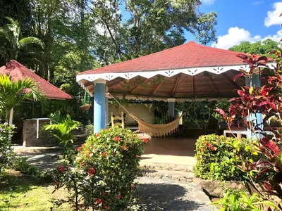 a gazebo with a hammock in a garden at Acogedora Casa Rural en plena naturaleza frente al Río con piscina Bonao in Bonao