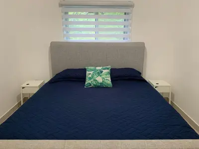 a bed with a blue comforter and a pillow on it at Furnished Apartment - Residencial Olas - Gated Community - 24 hr Security in San Felipe de Puerto Plata