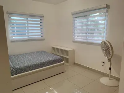 a bedroom with a bed and two windows and a fan at Furnished Apartment - Residencial Olas - Gated Community - 24 hr Security in San Felipe de Puerto Plata