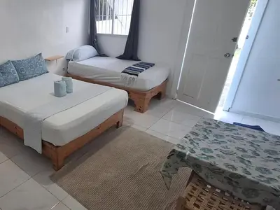 a room with two beds and a table in it at Apartamento Los Blancos, a dos Minutos de los Patos Barahona in Enriquillo