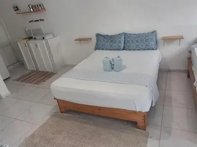 a bedroom with a large white bed with blue pillows at Apartamento Los Blancos, a dos Minutos de los Patos Barahona in Enriquillo