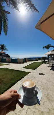 a person holding a cup of coffee on a table at Tritón Hotel Boutique & Restaurant in Guayacanes
