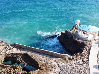 a boat sitting on the rocks next to the ocean at Tritón Hotel Boutique & Restaurant in Guayacanes