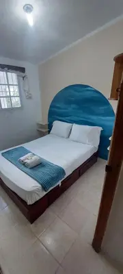 a bedroom with a large bed with a blue headboard at Apto Los Blancos, a dos Minuto de los Patos in Bejuquero