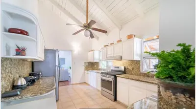 a kitchen with white cabinets and a ceiling fan at Lux Villa Casa de Campo in La Romana