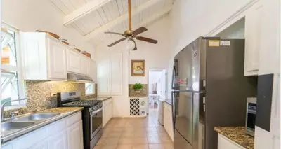 a kitchen with white cabinets and a ceiling fan at Lux Villa Casa de Campo in La Romana
