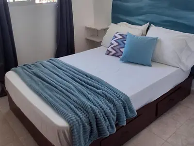 a bed with a blue blanket on top of it at Apto Los Blancos, a dos Minuto de los Patos in Bejuquero