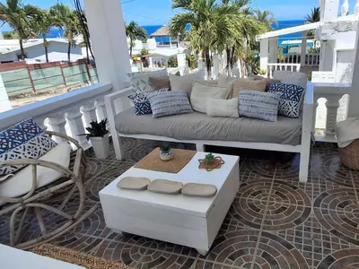 a porch with a couch and a chair on a balcony at Apto Los Blancos, a dos Minuto de los Patos in Bejuquero