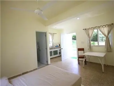 a bedroom with a bed and a table and a desk at Bungalow #1 at Waterfront Playa Alicia in Sosúa