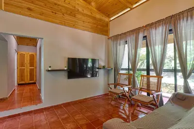 a living room with chairs and a tv and windows at Casa Kafe in Cabrera
