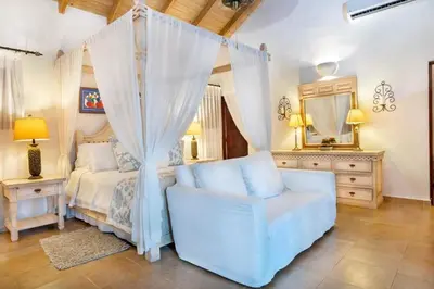 a bedroom with a bed and a chair and a mirror at Los Lagos 19 - Sleeps 10 - Butler - Pool Hot Tub in La Romana