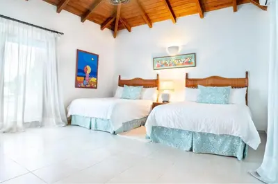 two beds in a room with white walls at Los Lagos 19 - Sleeps 10 - Butler - Pool Hot Tub in La Romana