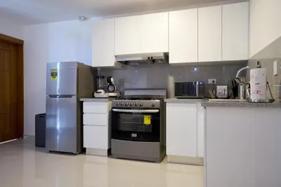 a kitchen with white cabinets and stainless steel appliances at Apartments in La Julia 1 and 2 Bedrooms in Santo Domingo