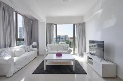 a white living room with a white couch and a tv at Apartments in La Julia 1 and 2 Bedrooms in Santo Domingo