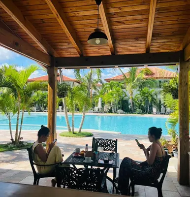 two women sitting at a table near a pool at Residencial Paraiso Bayahibe in Bayahibe
