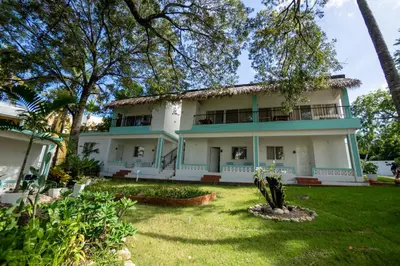 a large white house with trees in the yard at Bungalow #14 at Waterfront Playa Alicia in Sosúa