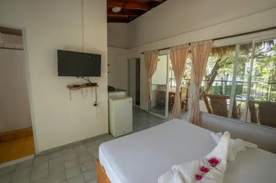 a bedroom with a bed and a flat screen tv at Bungalow #16 at Waterfront Playa Alicia in Sosúa