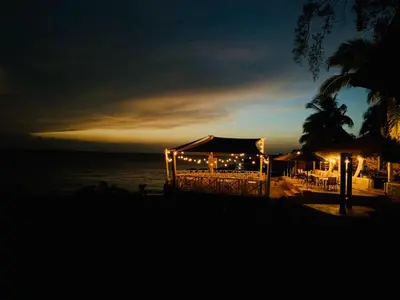 a restaurant with lights on the beach at night at Apartment #21 at Waterfront Playa Alicia in Sosúa