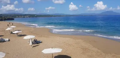 a beach with white umbrellas and the ocean at Apartment #21 at Waterfront Playa Alicia in Sosúa