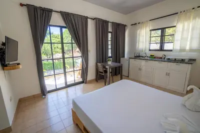 a bedroom with a large white bed and a kitchen at Room #23 at Waterfront Playa Alicia in Sosúa