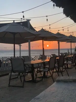 a group of tables and chairs with umbrellas on the beach at Bungalow #3 at Waterfront Playa Alicia in Sosúa