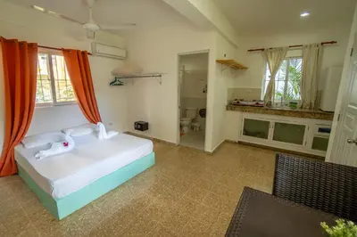 a bedroom with a white bed and a bathroom at Bungalow #9 at Waterfront Playa Alicia in Sosúa