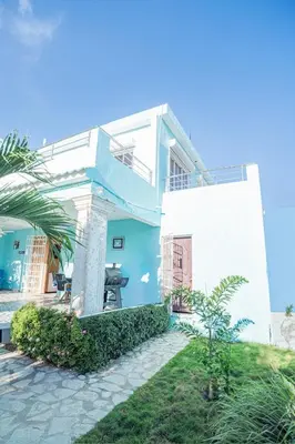 a white house with a palm tree in front of it at Villa Nilsa ( The Blue House ) in Baní