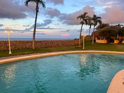 a swimming pool in front of a beach with palm trees at Ocean Breeze Villa Carismar in Cabrera