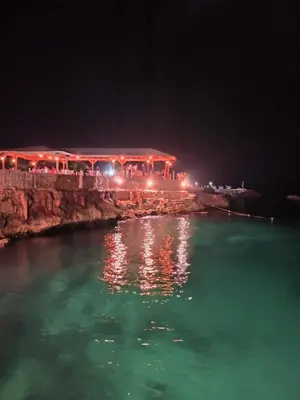 a building with lights on the water at night at Estudio Frente al Mar Solo Adultos in La Laguna