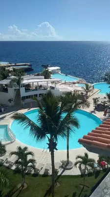 a large pool with palm trees and the ocean at Sol Dominicus 1 Apartamento con Cocina Solo Adultos in La Laguna