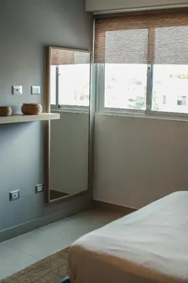 a bedroom with a bed and a mirror and windows at ARMONIA 408 APARTMENT IN GAZCUE in Santo Domingo