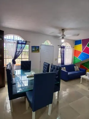 a living room with a glass table and blue chairs at Villa Boutique con Piscina Privada a Minutos del Aeropuerto SDQ in Boca Chica