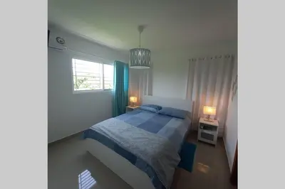 a bedroom with a bed with blue sheets and a window at Confortable apartamento de 3 tres habitaciones, con hermosa vista de area verde, ademas de piscinas y juegos infantiles en area recreativa in Santiago de los Caballeros