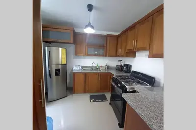 a kitchen with wooden cabinets and stainless steel appliances at Confortable apartamento de 3 tres habitaciones, con hermosa vista de area verde, ademas de piscinas y juegos infantiles en area recreativa in Santiago de los Caballeros