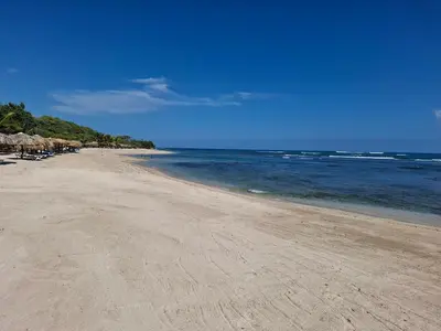 a sandy beach with umbrellas and the ocean at Costambar Beach Seaside Apartment in San Felipe de Puerto Plata