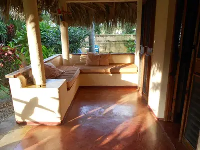a porch of a house with a couch and a window at Palm-covered house in the tropical -Casa Oli in Las Galeras