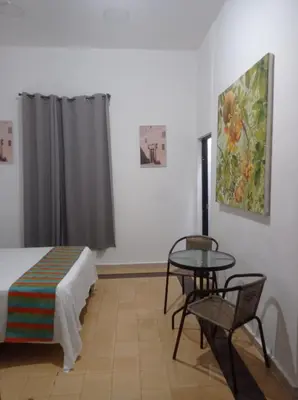 a room with a bed and a table and a painting at Hostal Mi Rincón in Santo Domingo