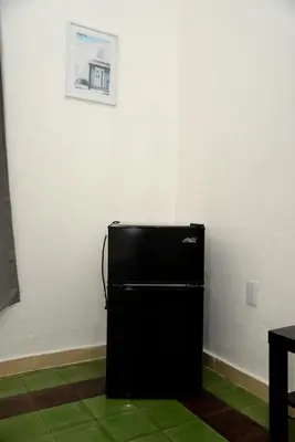 a black refrigerator in a room with a picture on the wall at Hostal Mi Rincón in Santo Domingo