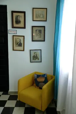 a yellow chair in a room with pictures on the wall at Hostal Mi Rincón in Santo Domingo