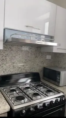 a stove top oven in a kitchen next to a microwave at Cozy Apartment near Downtown Center in Santo Domingo