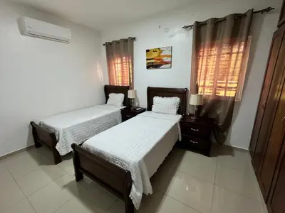 a bedroom with two beds and two windows at Paramount 3-Bedroom Apartment with Parking in San Felipe de Puerto Plata