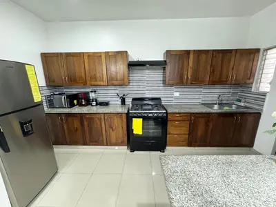 a kitchen with wooden cabinets and a black stove at Paramount 3-Bedroom Apartment with Parking in San Felipe de Puerto Plata