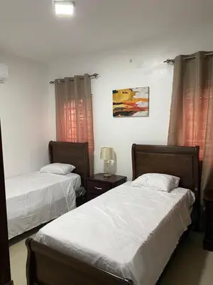 a bedroom with two beds and a table with a lamp at Paramount 3-Bedroom Apartment with Parking in San Felipe de Puerto Plata
