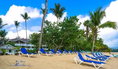 a row of chairs on a beach with palm trees at Hotel Residence Marilar in Las Terrenas
