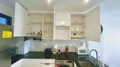 a kitchen with white cabinets and a washer at Cana Rock Star Pool View Whith BBQ in Punta Cana