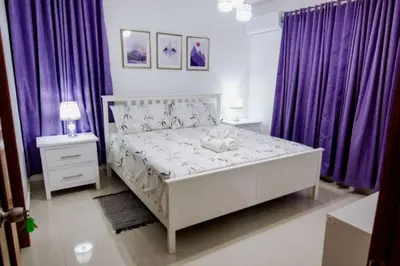 a bedroom with a white bed and purple curtains at Hermoso apartamento, 3 Habitaciones espaciosas, 2 Aires acondicionados in Santiago de los Caballeros